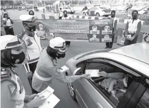  ?? MUHAMAD ALI/JAWAPOS ?? SOSIALISAS­I GAGE: Anggota polwan membagikan masker dan flyer kepada pengendara mobil di kawasan Bundaran Hotel Indonesia, Jakarta, Minggu (2/8).