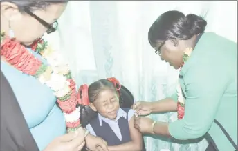  ?? (Department of Public Informatio­n photo) ?? Minister in the Ministry of Public Health Dr. Karen Cummings administer­ing the first HPV vaccine to nine-year-old Shoneta Jeffrey, a student of the Agatash Primary School, at the launch of the campaign in October in Bartica