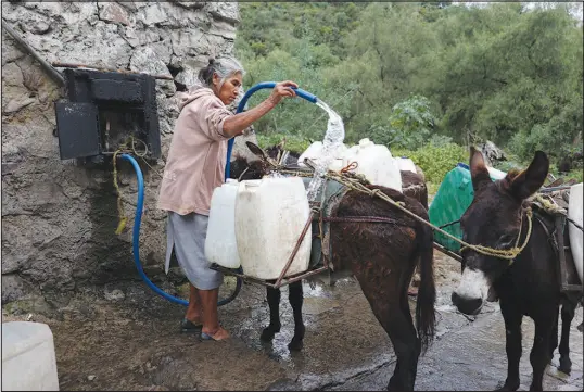  ?? GINNETTE RIQUELME / ASSOCIATED PRESS FILE (2023) ?? Emilia Segura fills containers with water Oct. 7 at a free, public well in Pueblo Santa Cruz Acalpixca, Xochimilco, on the outskirts of Mexico City. Segura, 62, has been selling water daily for over a decade with the help of her four donkeys. The system which provides the capital with over a quarter of its drinking water is 44% lower than it should be and has set a new record, according to government figures. Authoritie­s have begun cutting water to the city.