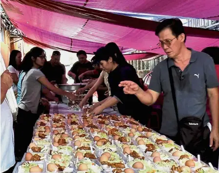  ??  ?? Helping hands: Sam (right) and other volunteers preparing food to be distribute­d to the poor and hungry.