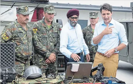  ?? ROMAN KOKSAROV THE ASSOCIATED PRESS ?? Prime Minister Justin Trudeau, right, and Defence Minister Harjit Singh Sajjan inspect equipment at the Adazi military base in Latvia on Tuesday.
