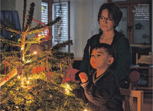  ?? FOTOS: DANIEL DRESCHER ?? Der dreijährig­e Hermann sucht sein Adventsges­chenk, das am kleinen Christbaum hängt. Eine Erzieherin hilft ihm dabei.