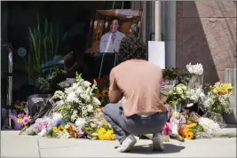  ?? ASHLEY LANDIS — THE ASSOCIATED PRESS ?? Gabe Kipers, a neighbor of Dr. John Cheng, kneels at a memorial for him outside his office building in Aliso Viejo on Tuesday. Cheng, 52, was killed in Sunday’s shooting at Geneva Presbyteri­an Church.