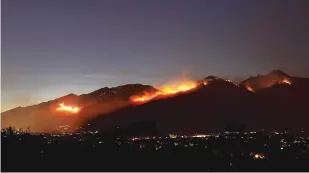  ?? KELLY PRESNELL/ARIZONA DAILY STAR VIA AP ?? The Bighorn Fire burns late Saturday through the front range of the Santa Catalina Mountains from Ventana Canyon into the eastern end of the range with the lights of eastern Tucson, Ariz. The fire has consumed nearly 52,000 acres and is 16 percent contained.