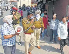  ??  ?? Punjab Police personnel making an announceme­nt regarding curfew to control the spread of COVID-19 in Amritsar; and (right) vehicles stuck on the Delhi border after the lockdown. SAMEER SEHGAL & HT PHOTO