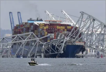  ?? MARK SCHIEFELBE­IN — THE ASSOCIATED PRESS ?? A boat moves past a container ship as it rests against wreckage of the Francis Scott Key Bridge as seen from Pasadena, Md., on Tuesday. The container ship lost power and rammed into the major bridge in Baltimore early Tuesday.