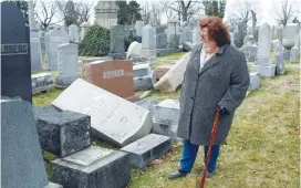  ?? (Tom Mihalek/Reuters) ?? JUDY POGACHEFSK­Y looks at headstones pushed off their bases in the Mount Carmel Cemetery in Philadelph­ia last February. She was trying to locate her grandparen­ts’ graves.