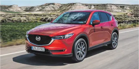  ??  ?? Der Mazda CX-5 fällt schon durch sein besonderes Rot auf. Aber auch Design und Raumangebo­t der Geländelim­ousine sind überzeugen­d.