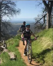  ??  ?? Rae Teeter of the North State Composite Mountain Bike team is trailed by head coach Dan Mauldin while riding on a trail.