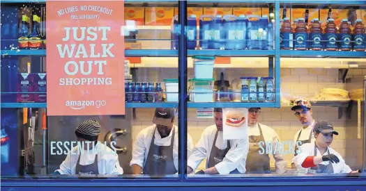  ?? AP PHOTO/ELAINE THOMPSON ?? Workers make sandwiches at an Amazon Go in Seattle. One executive said she was surprised at customers who were reluctant to just leave after shopping.