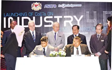  ??  ?? Riot (standing, centre) and Ahmad Maslan (standing, third right) witness the signing of a Memorandum of Understand­ing between HRDF and PSDC.