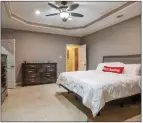  ?? ?? The spacious primary bedroom is equipped with a tray ceiling, a ceiling fan with a light, a walk-in closet and a sitting area with a window.