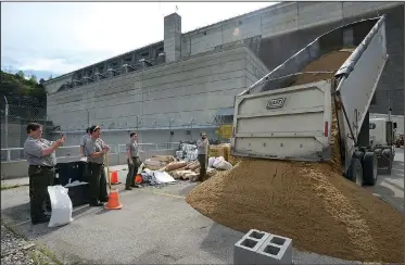  ?? NWA Democrat-Gazette/BEN GOFF • @NWABENGOFF ?? A truck dumps a load of sand as Beaver Lake park rangers fill sandbags Thursday at the Beaver Dam power plant near Eureka Springs. With heavy rain in the forecast for the weekend, Army Corps of Engineers staff are building barriers to protect the power...