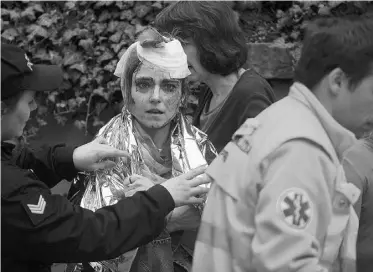  ?? MICHAL CIZEK/AFP/ GETTY IMAGES ?? A police officer and paramedic wrap a thermo foil around a woman injured by a powerful gas blast in Prague’s historic centre Monday. Dozens of people were injured, but no deaths were reported.