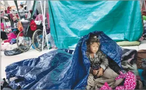  ?? AP PHOTO ?? A girl who travelled with the annual caravan of Central American migrants awakens where the group set up camp to wait for access to request asylum in the U.S., outside the El Chaparral port of entry building at the US-Mexico border in Tijuana, Mexico,...