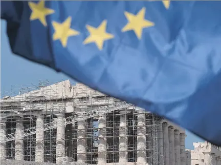  ?? LOUISA GOULIAMAKI/AFP/GETTY IMAGES ?? A European Union flag flies in front of the Parthenon in Athens on Thursday. Greek Prime Minister Alexis Tsipras has suggested he would resign if Greeks vote to accept austerity measures in a referendum to be held on Sunday.