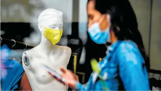  ?? Foto: Afp ?? Una chica pasa por delante de un maniquí femenino cuya cara aparece cubierta con una mascarilla.