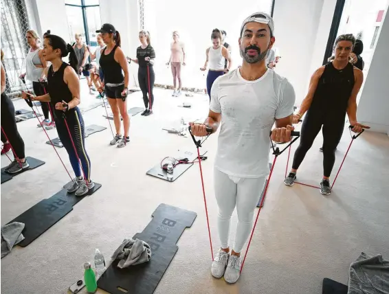  ?? Photos by Melissa Phillip / Staff photograph­er ?? Tootsies’ Fady Armanious and the group at Barry’s Bootcamp use resistance bands and body-weight exercises during their workout.