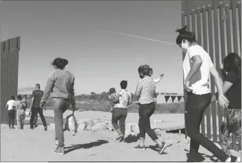  ?? EUGENE GARCIA/AP ?? A GROUP OF BRAZILIAN MIGRANTS MAKE THEIR WAY around a gap in the U.S.-Mexico border in Yuma, seeking asylum in the United States after crossing over from Mexico on June 8, 2021.