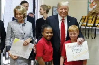  ?? ALEX BRANDON - THE ASSOCIATED PRESS ?? Above, President Donald Trump and Education Secretary Betsy DeVos pose with fourth graders Janayah Chatelier, 10, left, Landon Fritz, 10, after they received cards from the children, during a tour of Saint Andrew Catholic School, Friday, in Orlando,...