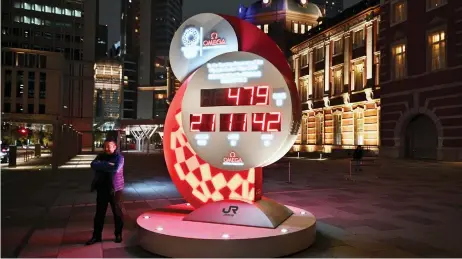  ?? — AFP photo ?? A countdown clock shows the adjusted time remaining for the postponed Tokyo Olympic Games outside Tokyo station, in Tokyo.