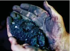  ?? AP FILE PHOTO/DAVID GOLDMAN ?? A coal miner holds coal running through a processing plant in Welch, West Virginia.