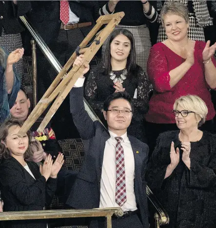  ?? AARON P. BERNSTEIN / BLOOMBERG ?? Ji Seong-ho, a North Korean defector and special guest of U. S. President Donald Trump, raises his crutches as Trump delivers the State of the Union address last Tuesday.