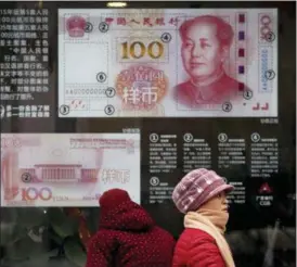  ?? ANDY WONG — THE ASSOCIATED PRESS ?? Women walk by a bank window panel displaying the security markers on the latest 100 Yuan notes Monday in Beijing. China’s policy ministry says it investigat­ed 380 online lenders and froze $1.5 billion in assets in a crackdown following an avalanche of scandals in the huge but lightly regulated industry.