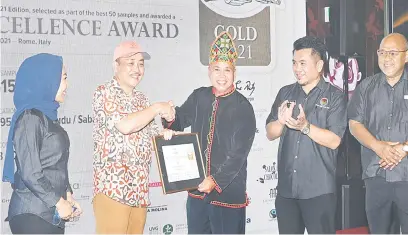  ?? ?? ANUGERAH: Hajiji (dua kiri) menyampaik­an Anugerah 2021 Cocoa of Excellence Award kepada Poimon Dangkat dari Kota Marudu sempena Pesta Koko Sabah 2022.