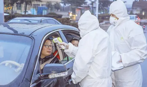  ??  ?? Medical staff members check the temperatur­e of a driver at a highway checkpoint in Tengzhou in China’s eastern Shandong province yesterday.