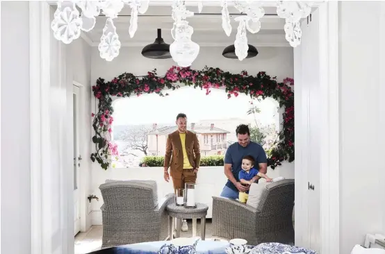  ??  ?? BALCONY Proud dads Ben (left) and Josh with their son Brooklyn. Bougainvil­lea frames the view. FOYER Antique chandelier. The inlay cabinet is a family piece. Eichholtz table, James Said. Flowers by Mr Cook (throughout). SHELVES This bookcase, in the living room, houses special pieces the couple have collected on their travels.