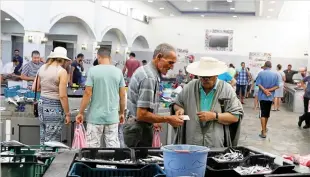  ??  ?? A vendor sells fish to customers at a central market in Mehdia, Tunisia. (Reuters)