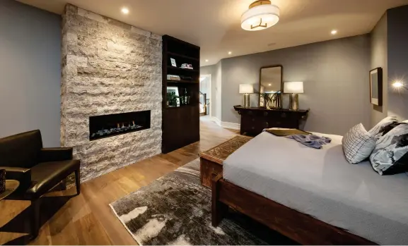  ??  ?? Walnut built-ins provide consistent function and warmth in the master bedroom where chiseled-edge ledge stone clads the gas fireplace.