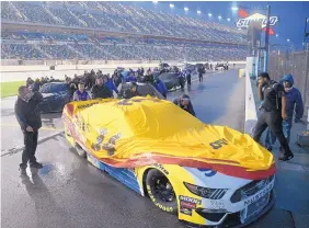  ?? PHELAN EBENHACK/ASSOCIATED PRESS ?? Crew members for driver Michael McDowell push his car to the garage after the race at Daytona Internatio­nal Speedway was postponed because of inclement weather.