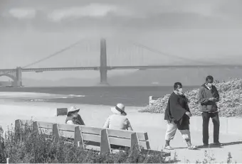  ?? NOAH BERGER/AP ?? Walkers wear masks while strolling at Crissy Field East Beach in San Francisco on Oct. 22.