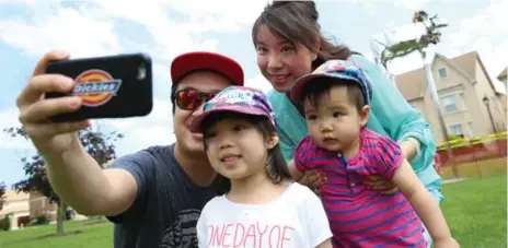  ?? RENÉ JOHNSTON/TORONTO STAR ?? Family Alan Ho, Bonnie Tam, Caileigh Ho, 4, and Danielle Ho, 1, take a family photo with Charity, the three-story statue that is drawing people to the park.