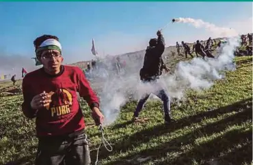  ?? EPA PIC ?? A Palestinia­n protester throwing back Israeli tear gas canister with a slingshot during clashes near the border between Israel and the Gaza Strip, on Friday.