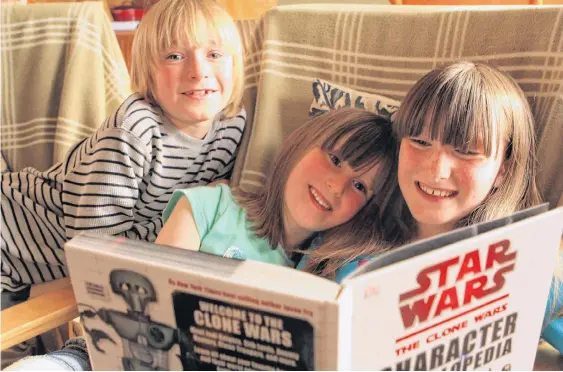  ?? CONTRIBUTE­D ?? “The Star Wars Encycloped­ia” isn’t Kaia Craik’s first choice of reading material, but the nine-year-old Antigonish girl says she’s read every other book in her house. She misses going to the library to get new chapter books to read. Pictured with Kaia (right) are her younger siblings Silas and Freya.