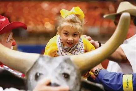  ?? Steve Gonzales / Houston Chronicle ?? Mary Elizabeth Washington mounts up for a ride on a wooden bull during the Houston Livestock Show and Rodeo Lil' Rustlers event for kids with special needs. The kids rode horses, pitched horseshoes and beanbags or tried their hands at roping.