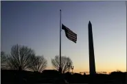  ?? JULIO CORTEZ - THE ASSOCIATED PRESS ?? In this 2019 file photo, a flag at the World War II Memorial flies upside down after it unclipped from its snaphook, before sunrise on Capitol Hill in Washington. At right is the Washington Monument.