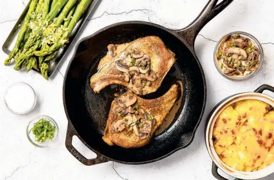  ?? EBERLY FILM LAB/THE DAILY MEAL PHOTOS ?? For your holiday meal, serve pork chops with a sauce of baby portabella mushrooms, along with creamy potato gratin and steamed asparagus.