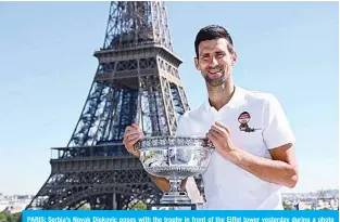  ??  ?? PARIS: Serbia’s Novak Djokovic poses with the trophy in front of the Eiffel tower yesterday during a photo call, a day after winning the Roland Garros 2021 French Open tennis tournament. —AFP