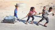  ?? MOHAMMED SALEM/REUTERS ?? Palestinia­n children pull water containers as people flee Rafah after Israeli forces launched a ground and air operation in the eastern part of the southern Gaza city Thursday.