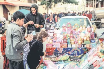  ?? — AFP photos ?? Palestinia­n children look at toys displayed by a street vendor in Gaza City, amid the ongoing conflict between Israel and Hamas militants, as Muslim worshipper­s prepare to welcome the holy fasting month of Ramadan which begins next week.