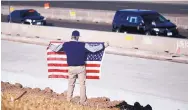  ?? DAVID ZALUBOWSKI/ASSOCIATED PRESS ?? David Morgan of Highlands Ranch, Colo., holds an American flag as a vehicle carrying the body of a sheriff’s deputy who was shot and killed Sunday drives by.