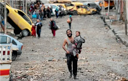  ?? PHOTO: REUTERS ?? In one of the defining images from the battle for Mosul, a father flees with his daughter from an Islamic State-controlled area of the city. Now that Isis has been defeated, local militia are taking revenge for their suffering.