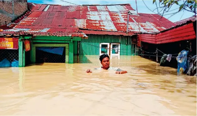  ?? Agence France-presse ?? ↑ A man leaves his flooded house on Monday in Tebing Tinggi, as thousands of houses were inundated in North Sumatra after torrential rain pounded the area.