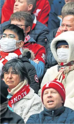  ?? Picture: PA. ?? Liverpool fans at Anfield wearing masks to protect themselves from coronaviru­s.