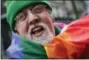  ?? AP PHOTO/MARK LENNIHAN ?? In this Monday, March 17, 2014, file photo, artist Gilbert Baker, designer of the Rainbow Flag, is draped with the flag while protesting at the St. Patrick’s Day parade in New York. Baker, creator of the flag that has become a widely recognized symbol...