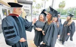  ?? JOE BURBANK/ORLANDO SENTINEL ?? Professor Peter Weishar talks with students from the University of Central Florida’s first class of masters-level Themed Experience on Friday.